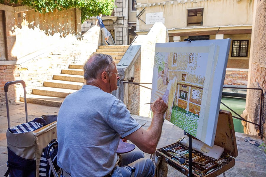 Artist painting one of the beautiful alleyways in Venice