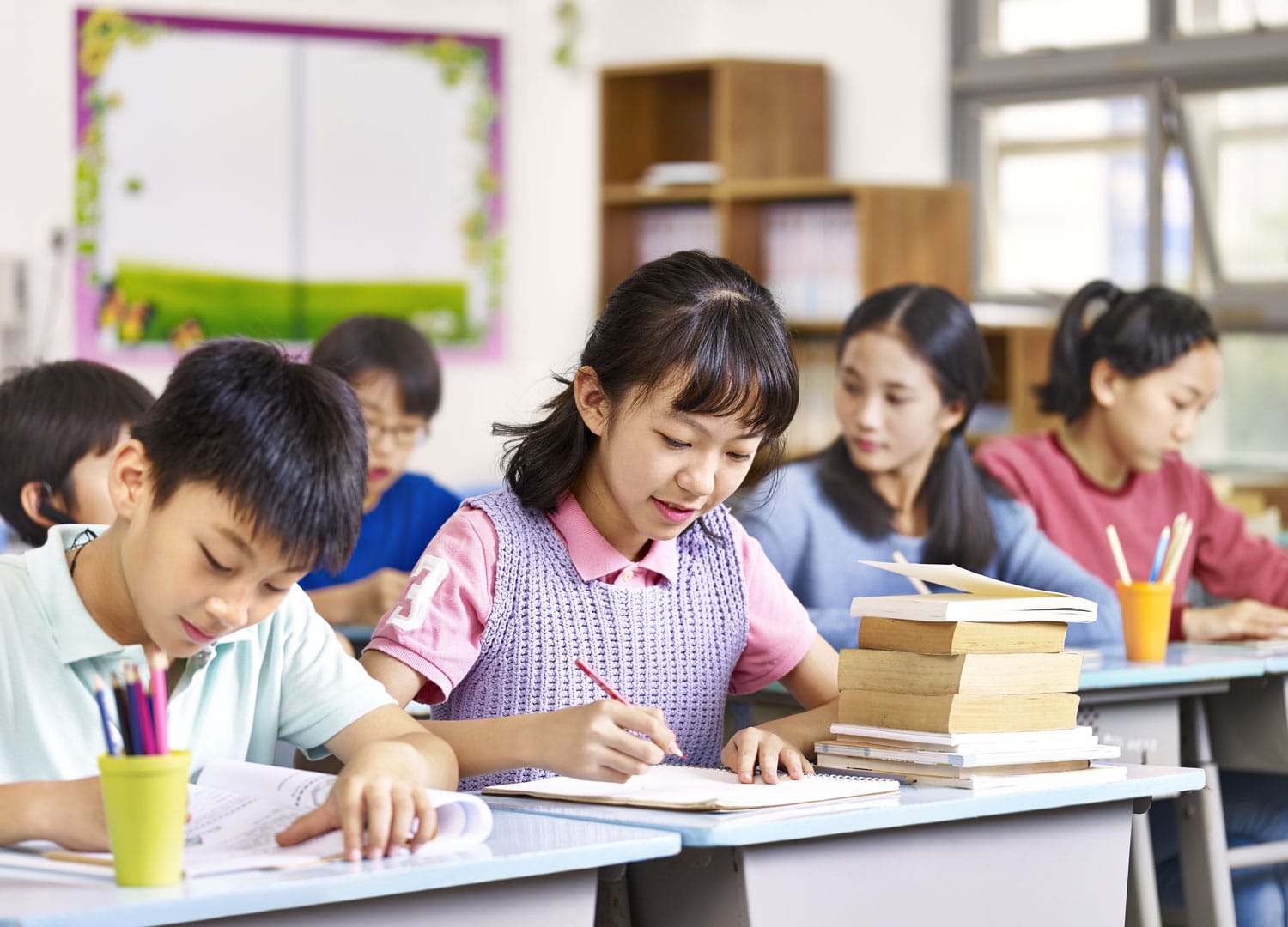 group of asian primary school boys and girls studying in class.