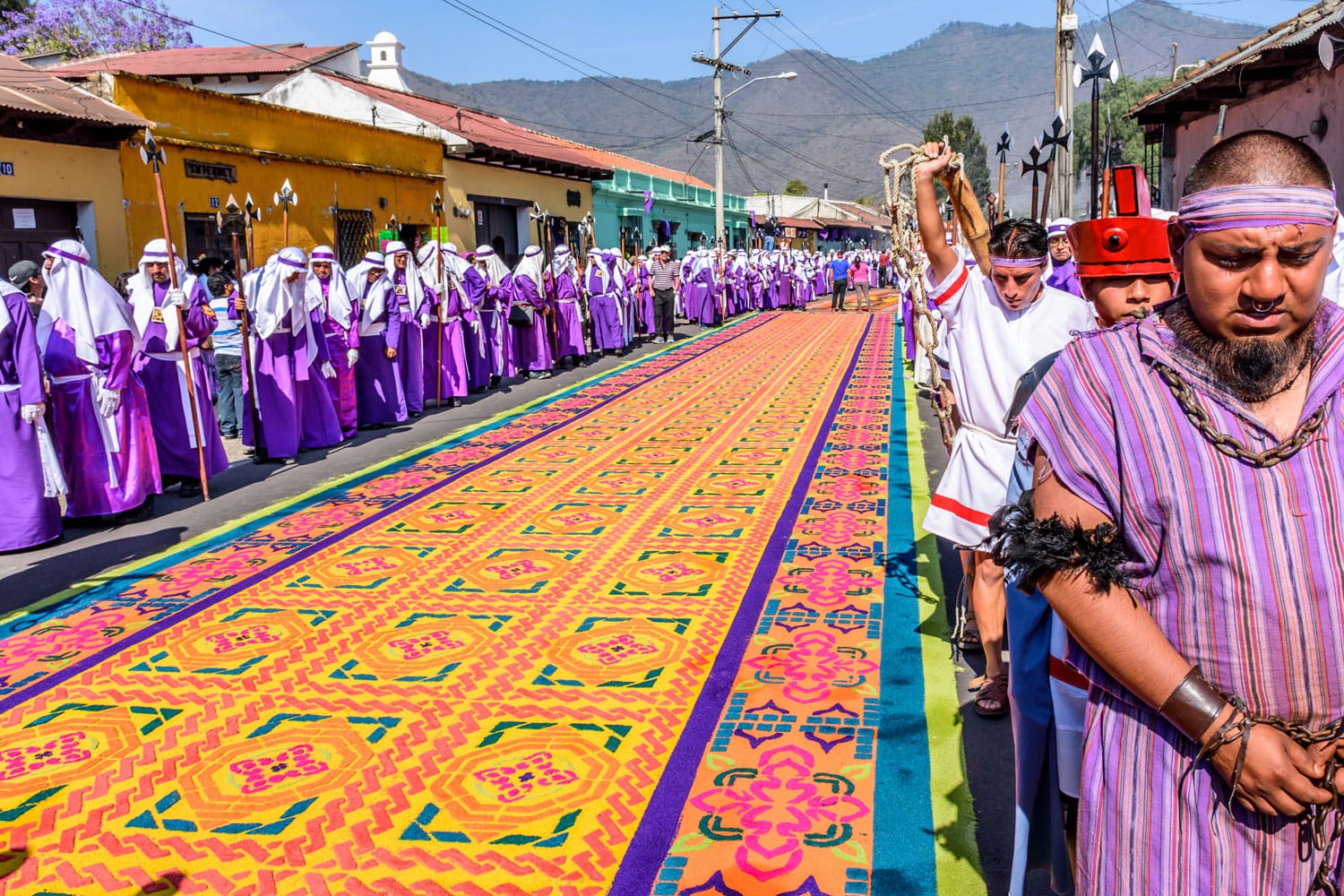 Locals reenact biblical scenes walking over handmade dyed sawdust carpets on Good Friday in colonial town with most famous Holy Week celebrations in Antigua, Guatemala