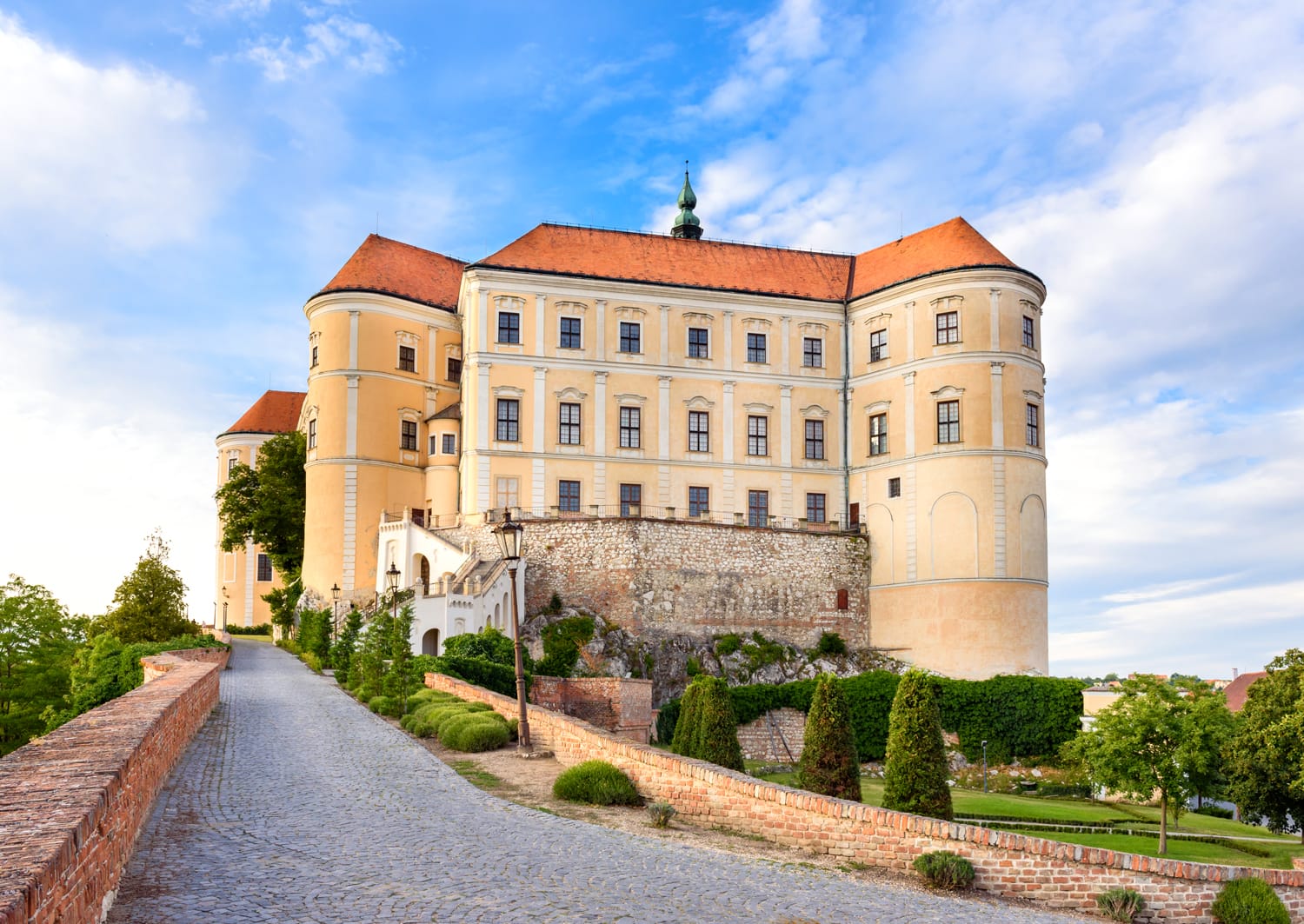Mikulov castle or Mikulov Chateau on top of rock. View from garden of castle with beautiful staircase and bright blue sky with clouds in background. Mikulov, Moravia, Czech Republic.