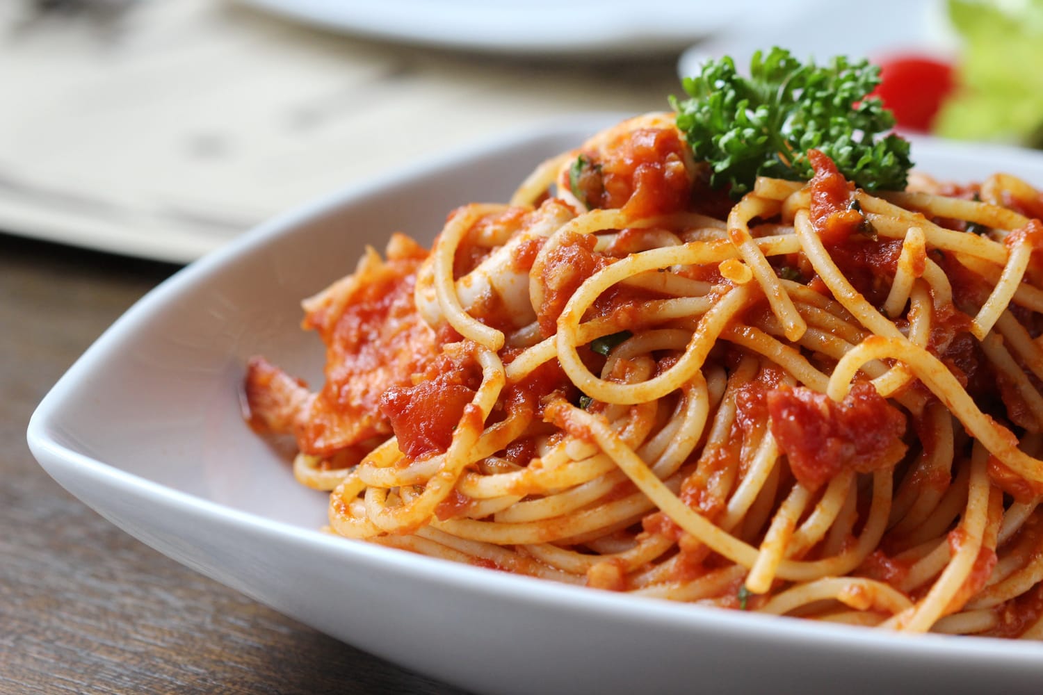 Low angle view of a serving of fresh Italian spaghetti with a meat based bolognese or bolognaise with tomato sauce on a plain white plate