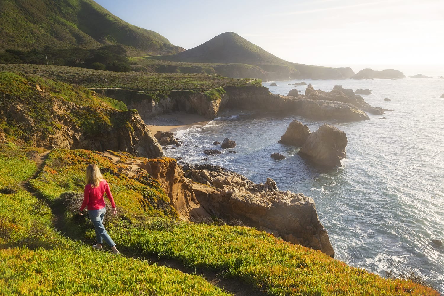 A female hiker walks down a trail in Big Sur, California.