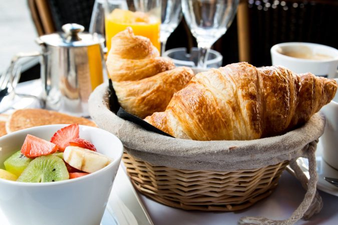 Breakfast with coffee and croissants in a basket on table