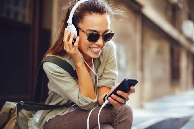 Young woman listening to music via headphones on the street