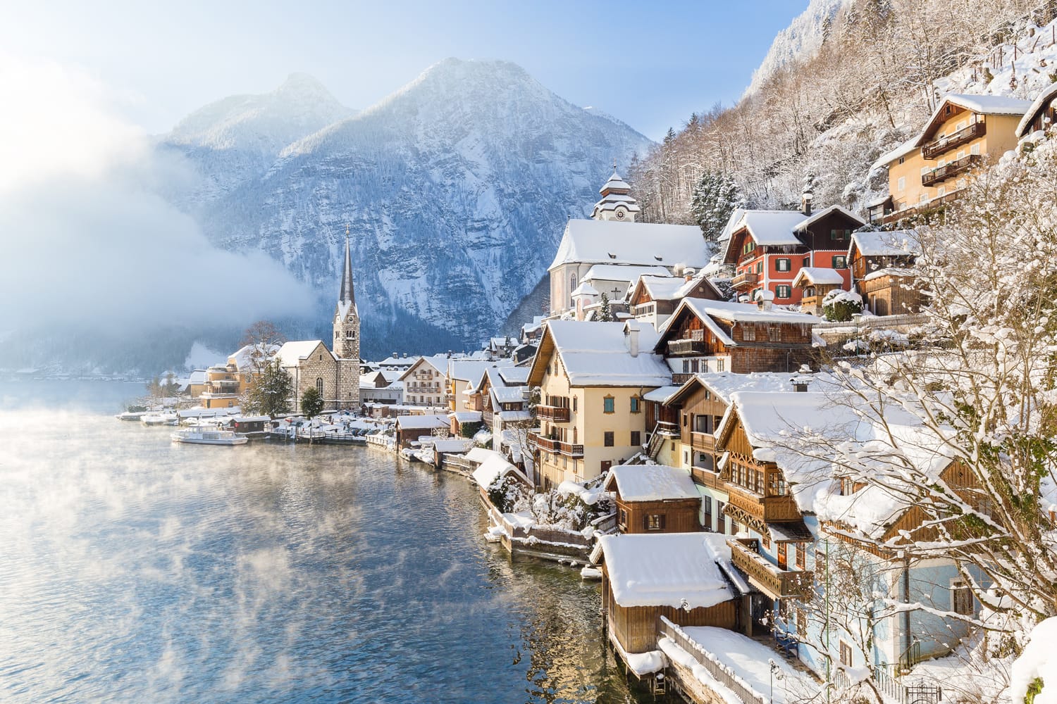Classic postcard view of famous Hallstatt lakeside town in the Alps with passenger ship on a beautiful cold sunny day with blue sky and clouds in winter, Salzkammergut region, Austria