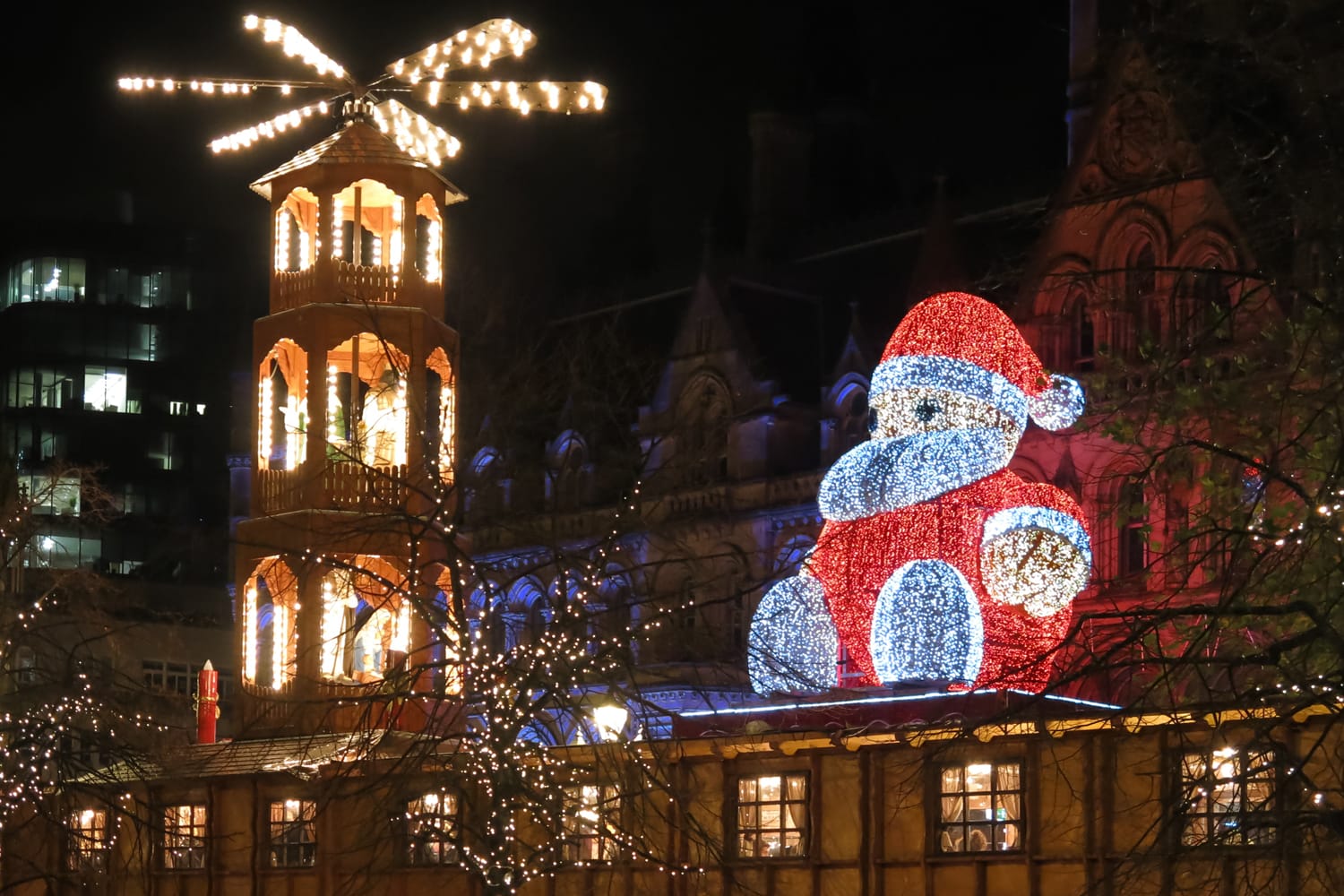 Santa Claus on Christmas market and town hall on Albert Square in Manchester at night.