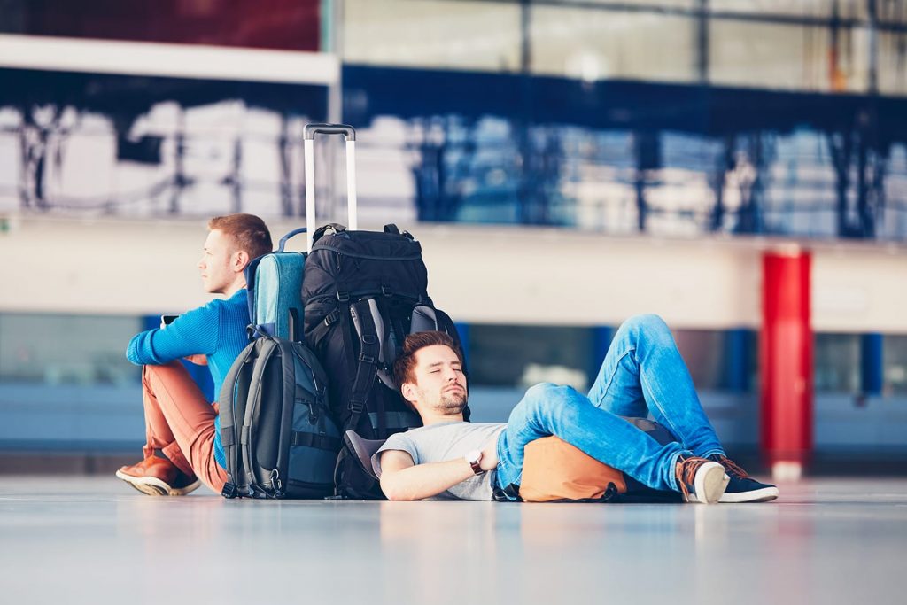 Two friends traveling together. Travelers waiting at the airport departure area for their delay flight