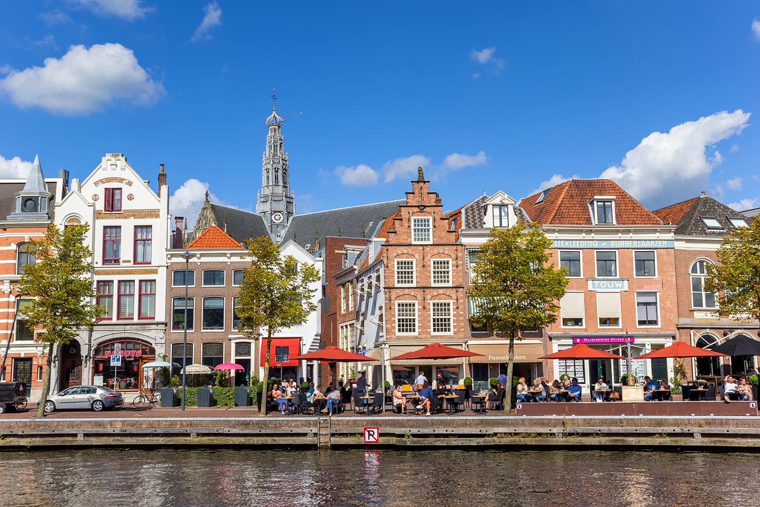People enjoying the sun at a historic canal in Haarlem, Netherlands