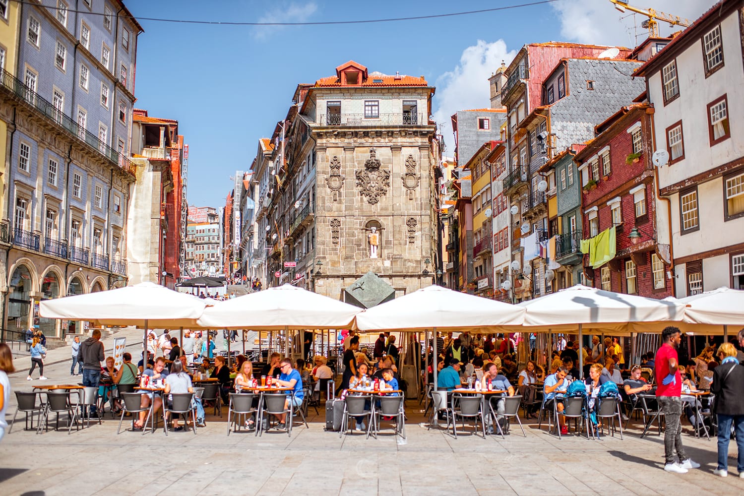 View on the Ribeira square with tourists sitting at the bars and restaurants in Porto city, Portugal