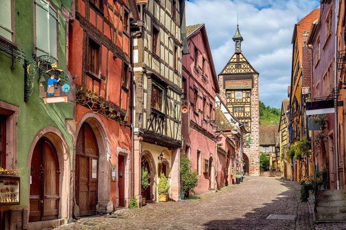 Central street of Riquewihr village with colorful traditional half-timbered french houses and Dolder Tower, Alsace, France