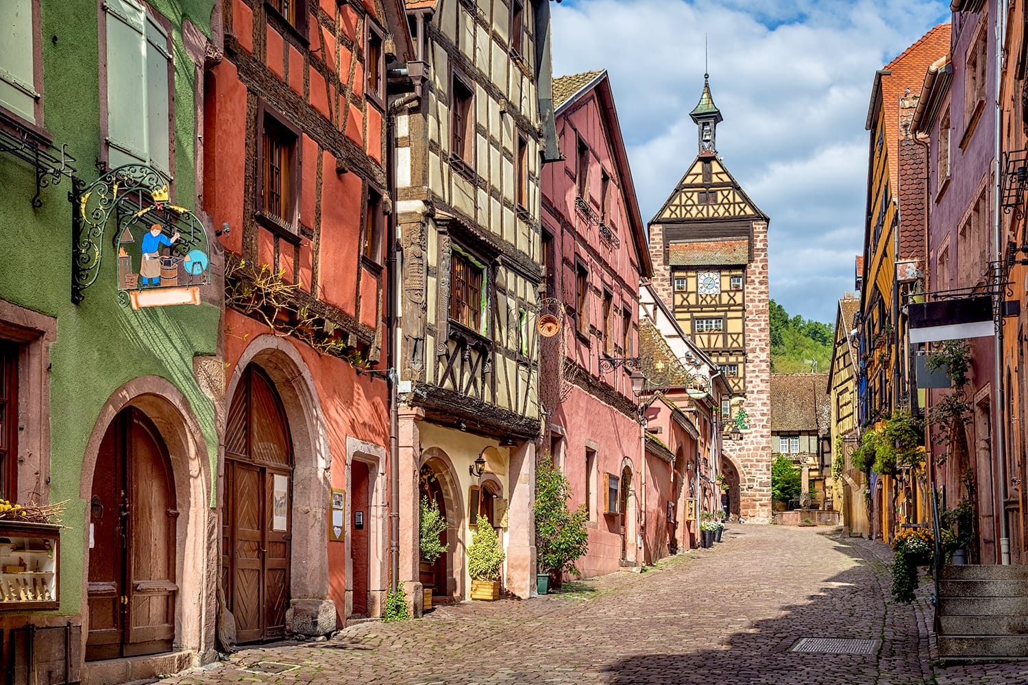 Central street of Riquewihr village with colorful traditional half-timbered french houses and Dolder Tower, Alsace, France