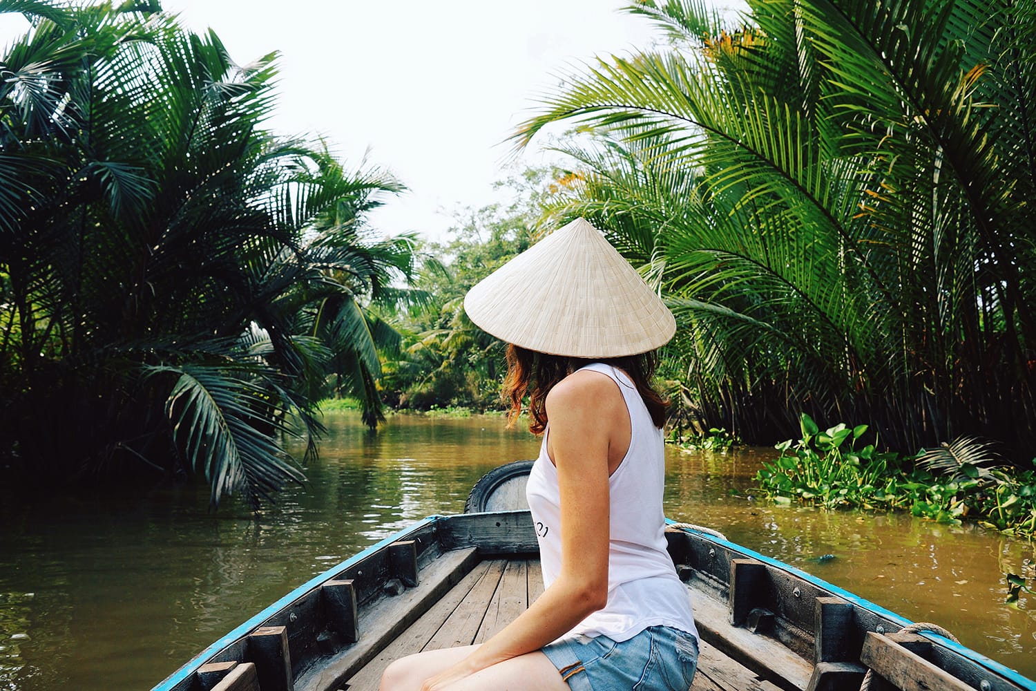 A young woman in a Vietnamese hat rides a boat on the Mekong River in Vietnam.The girl is traveling in a boat along the Mekong Delta in Vietnam.A serene river tour on the Mekong Delta, Can Tho Vietnam