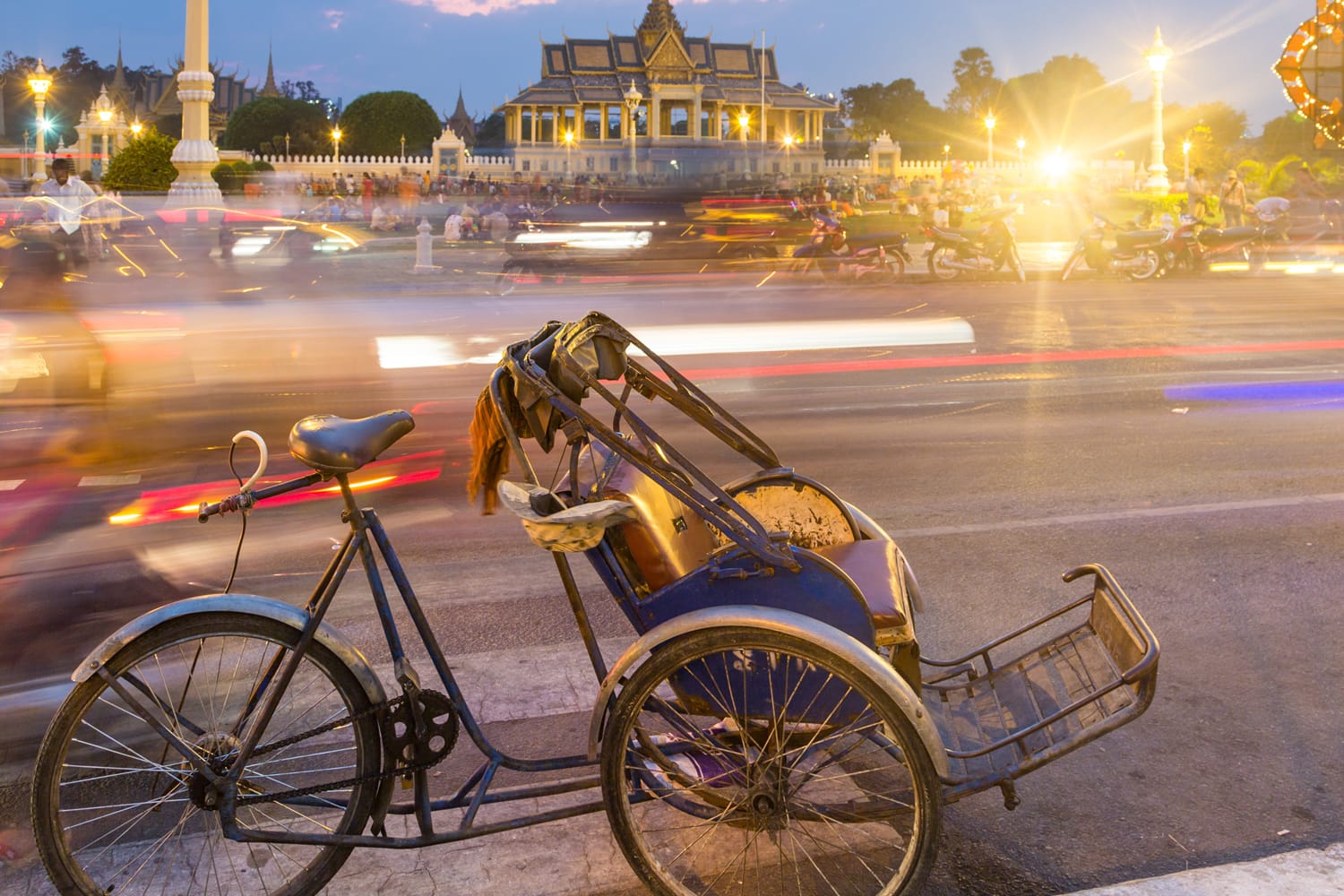 A bicycle rickshaw is parked in front of Phnom Penh Royal Palace in Cambodia capital city.