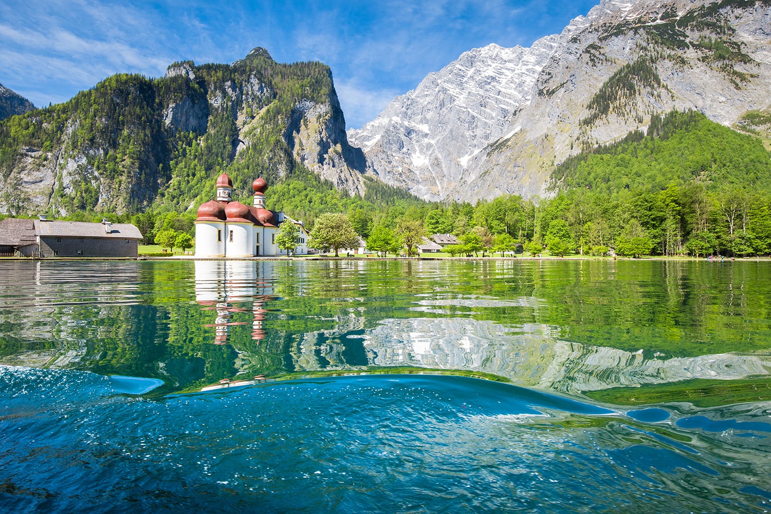 Classic panoramic view of Lake Konigssee with world famous Sankt Bartholomae pilgrimage church and Watzmann mountain on a beautiful sunny day in summer, Berchtesgadener Land, Bavaria, Germany
