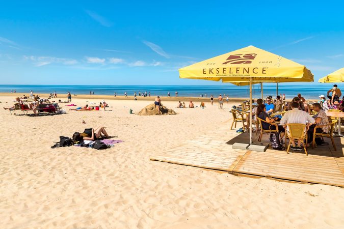 People enjoy the sunny spring day on the Baltic sea gulf beach in Jurmala resort, Latvia