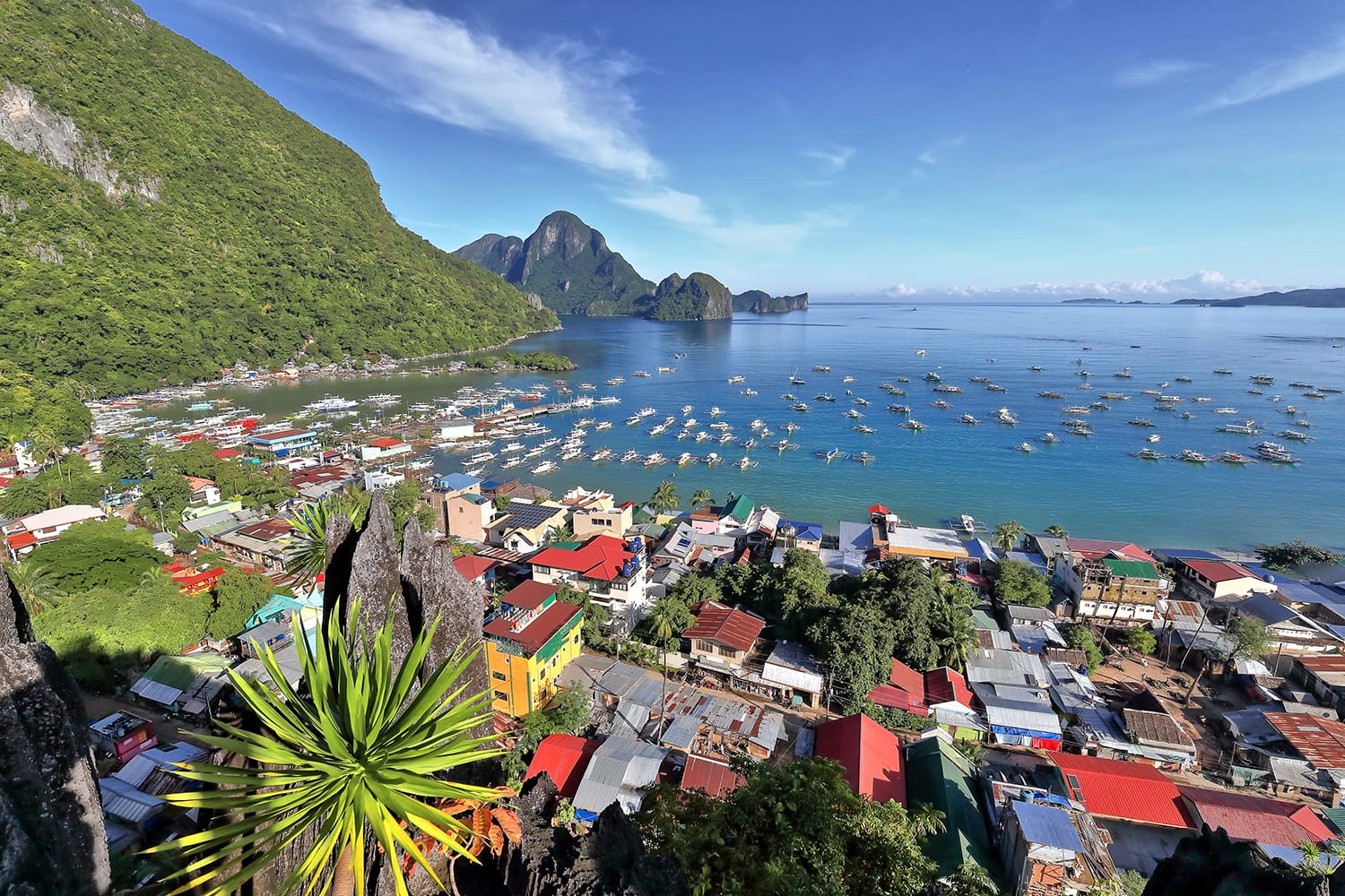 Northwards view from the observation deck at Taraw cliff over central El Nido town or Poblacion and further to the tourboat crowded port and bay with Cadlao island on background. Palawan-Philippines
