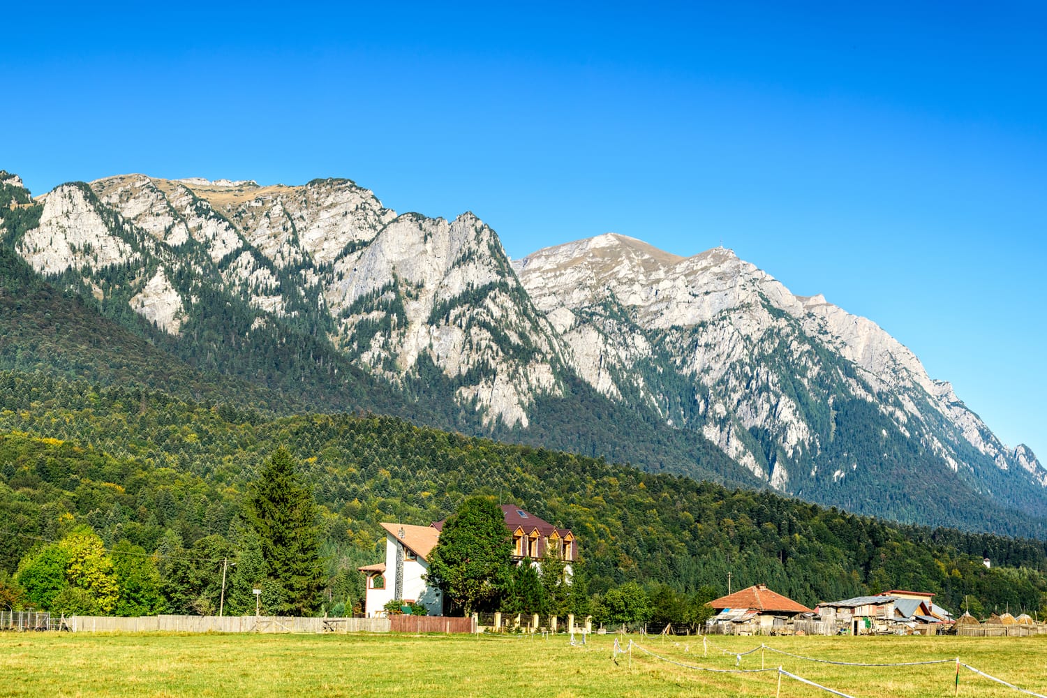 Carpathian Mountains, Romania. Sunny summer landscape with Bucegi steep with Caraiman Mount (2284 m) seen from Busteni, Prahova Valley