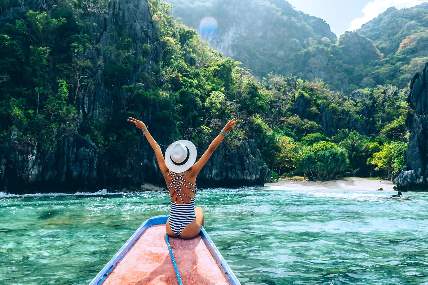Back view of the young woman in hat relaxing on the boat and looking at the island. Travelling tour in Asia: El Nido, Palawan, Philippines