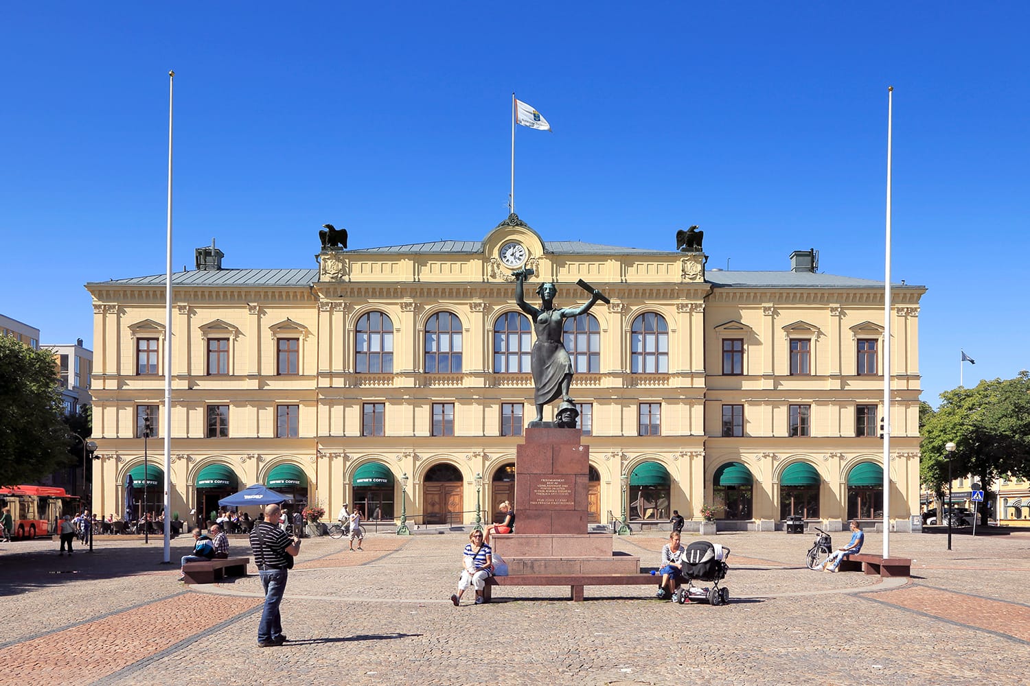 View of the main square with people and the old town hall behind the peace monument Freden during a sunny day with clear blue sky in Karlstad, Sweden