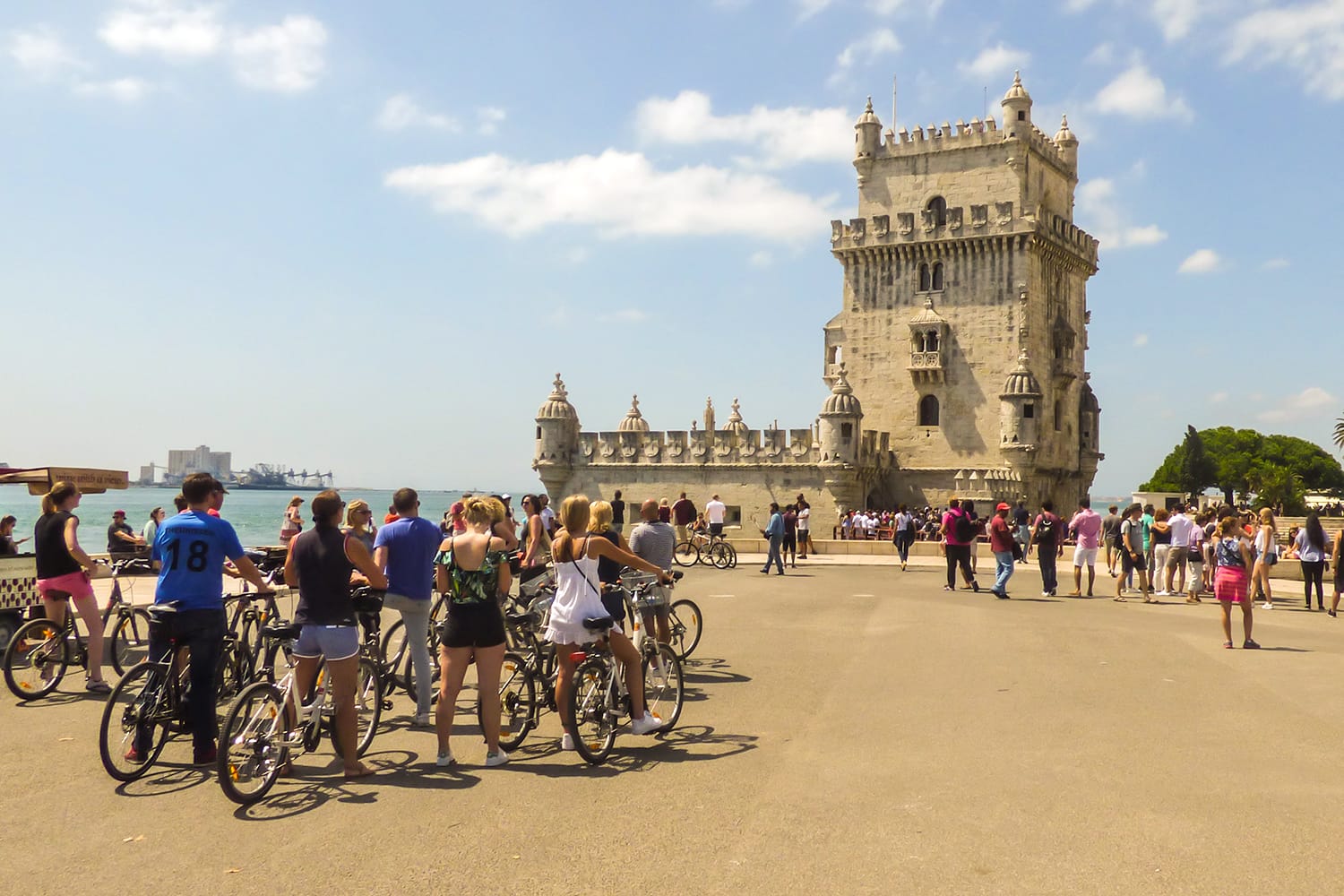 Crowd of tourists and people in bike tours around the Belem Tower, popular landmark in Lisbon, Portugal