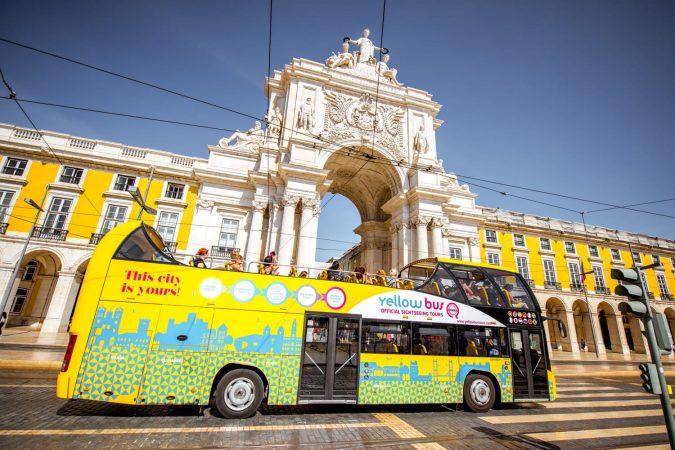 View on the Triumphal arch with tourist bus on the Commerce square during the sunrise in Lisbon city, Portugal