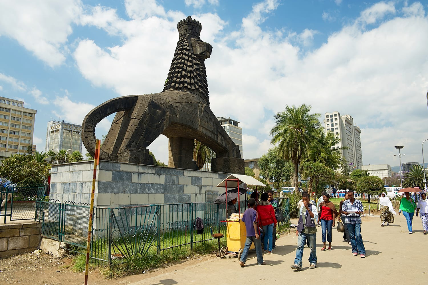 Unidentified people walk by the street next to the iconic statue of the Lion of Judah in Addis Ababa, Ethiopia.