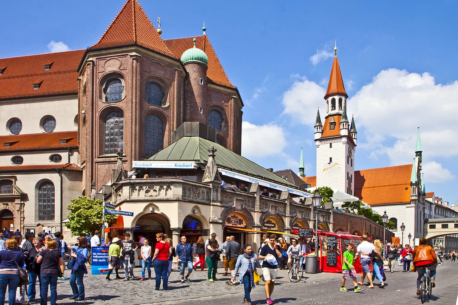 People stroll and shop in center Munich near the St. Peter church apse and the old city hall tower