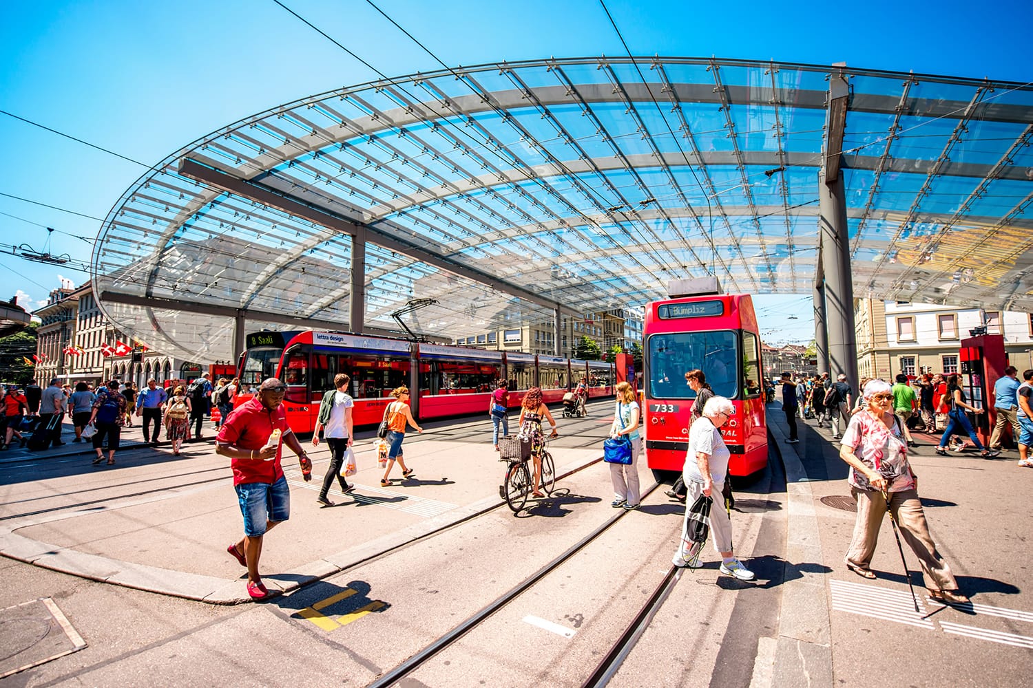 Modern tram station with red tram and people on Bubenberg place in the old town of Bern in Switzerland
