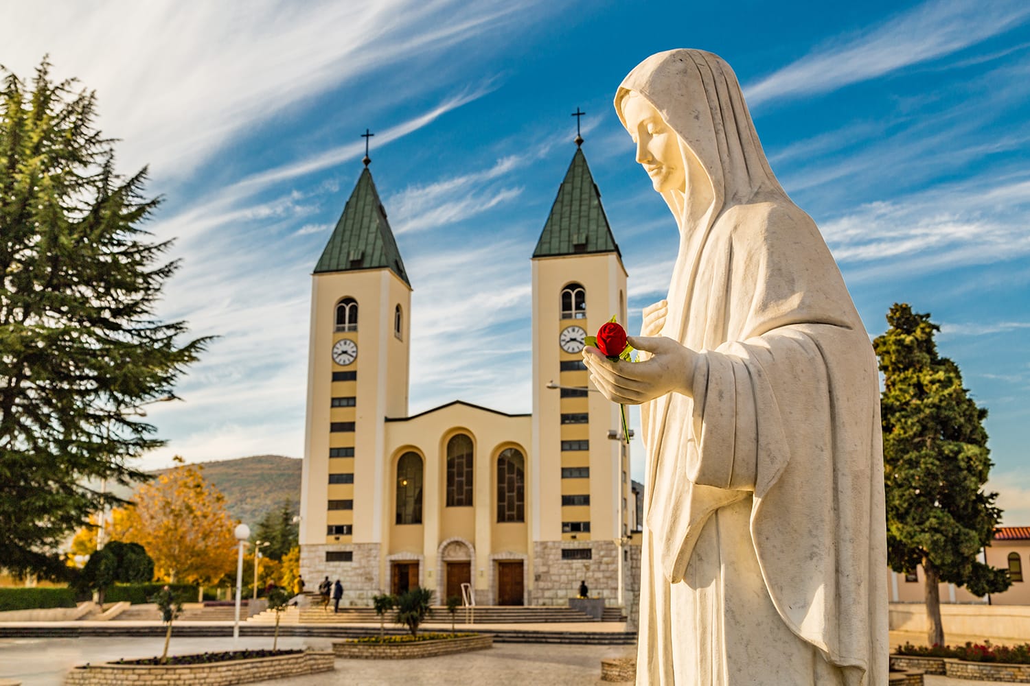 statue of the Blessed Virgin Mary holding a red rose while Saint James Church in Medjugorje, Bosnia & Herzegovina