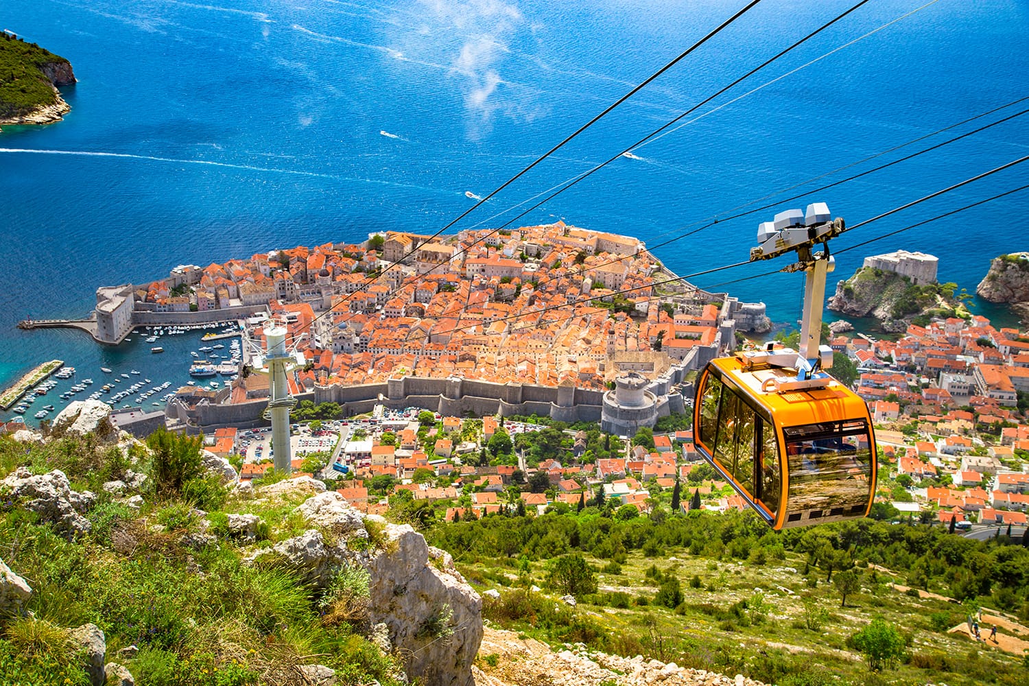 Aerial panoramic view of the old town of Dubrovnik with famous Cable Car on Srd mountain on a sunny day with blue sky and clouds in summer, Dalmatia, Croatia
