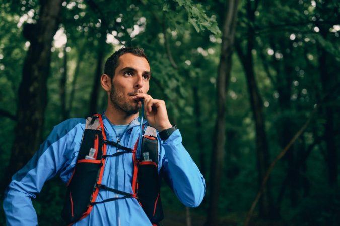 Man running and drinking from hydration pack
