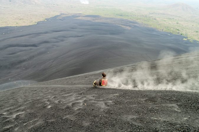 Tourist is volcano boarding from Cerro Negro volcano, Nicaragua
