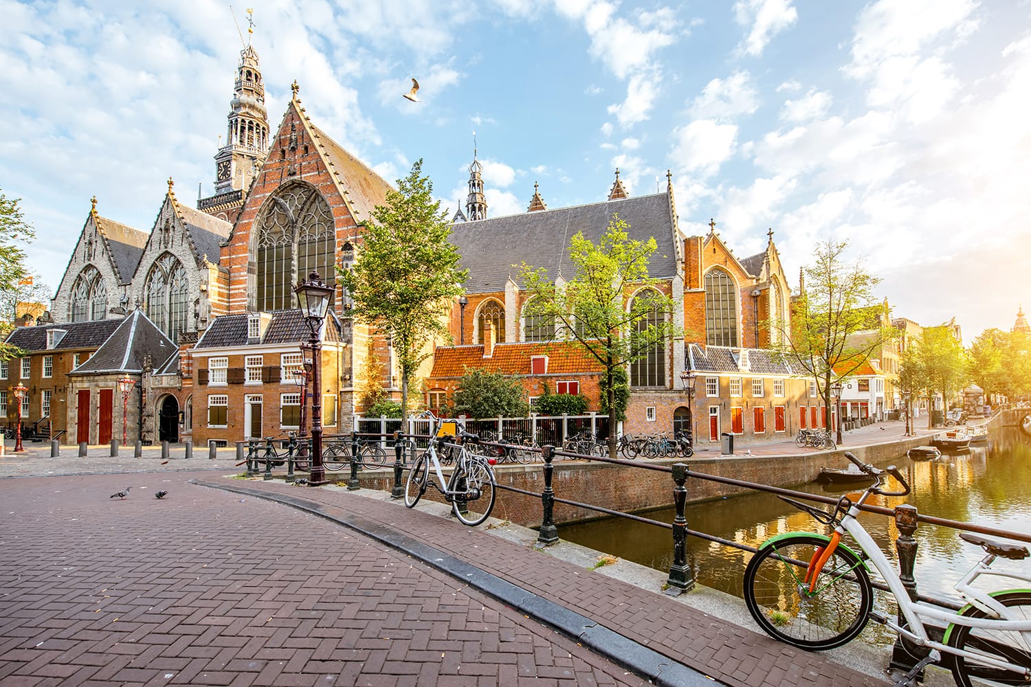 Morning view on the water channel with Old Church during the sunny weather in Amsterdam city