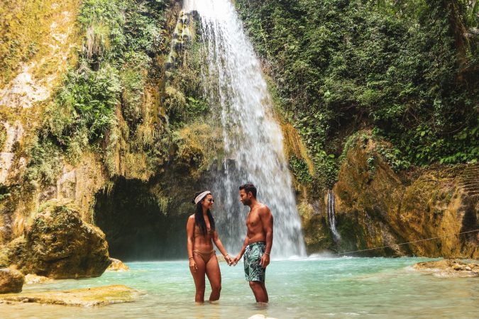 Lovely couple alone in deep forest waterfall from mountain gorge at hidden tropical jungle in Cebu Island in Philippines