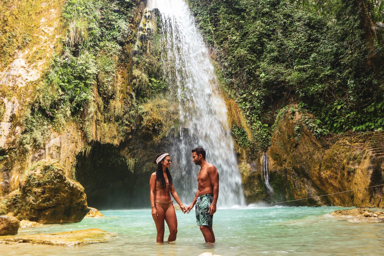 Lovely couple alone in deep forest waterfall from mountain gorge at hidden tropical jungle in Cebu Island in Philippines