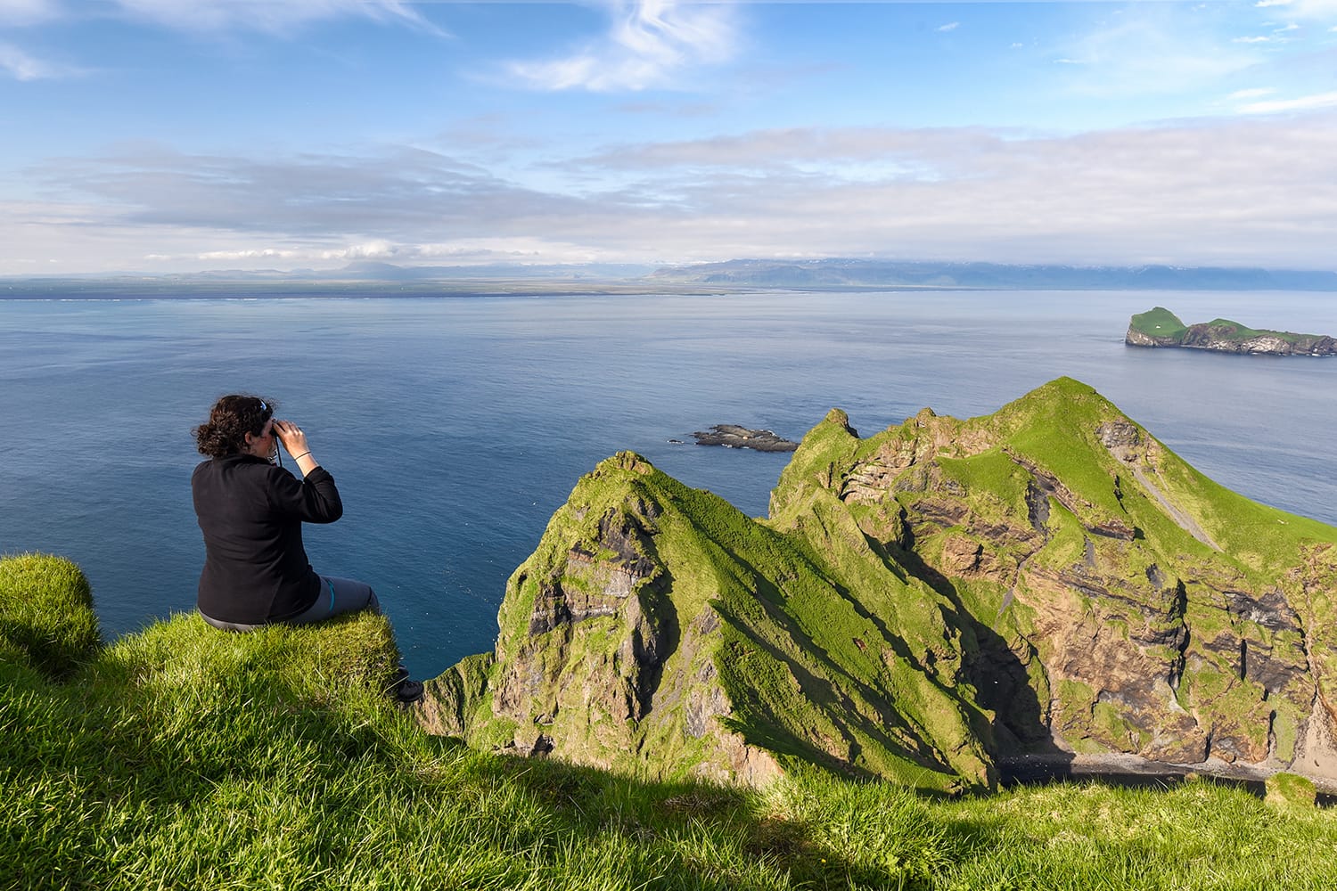 Hiker woman watching the sunset over Heimaey cliffs (Vestmann Islands - south of Iceland)