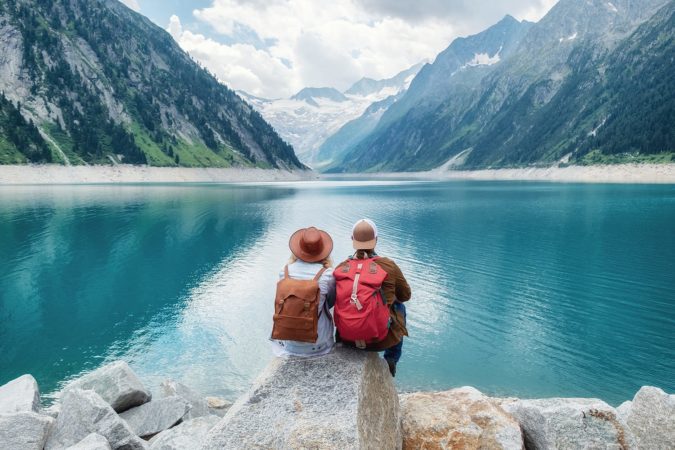 Travelers couple look at the mountain lake. Travel and active life concept with team. Adventure and travel in the mountains region in the Austria