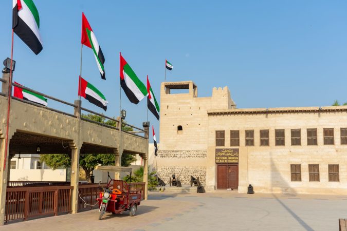 Entrance of the Ras al Khaimah Museum in the morning sun with flags blowing