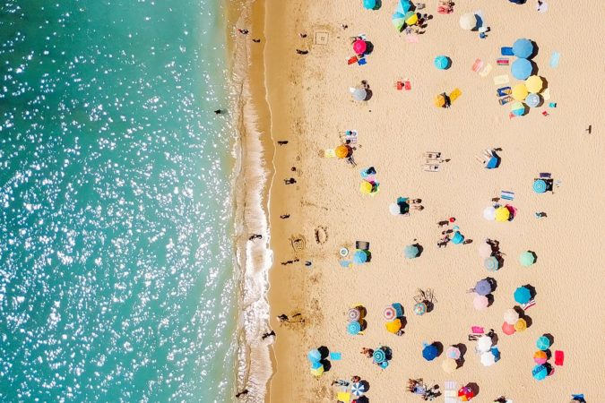 Aerial View From Flying Drone Of People Crowd Relaxing On Beach In Portugal
