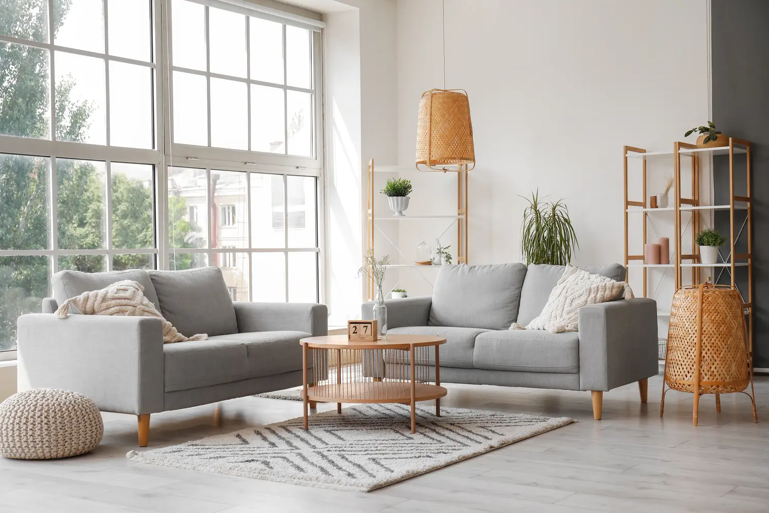 Interior of light living room with grey sofas, coffee table and large window