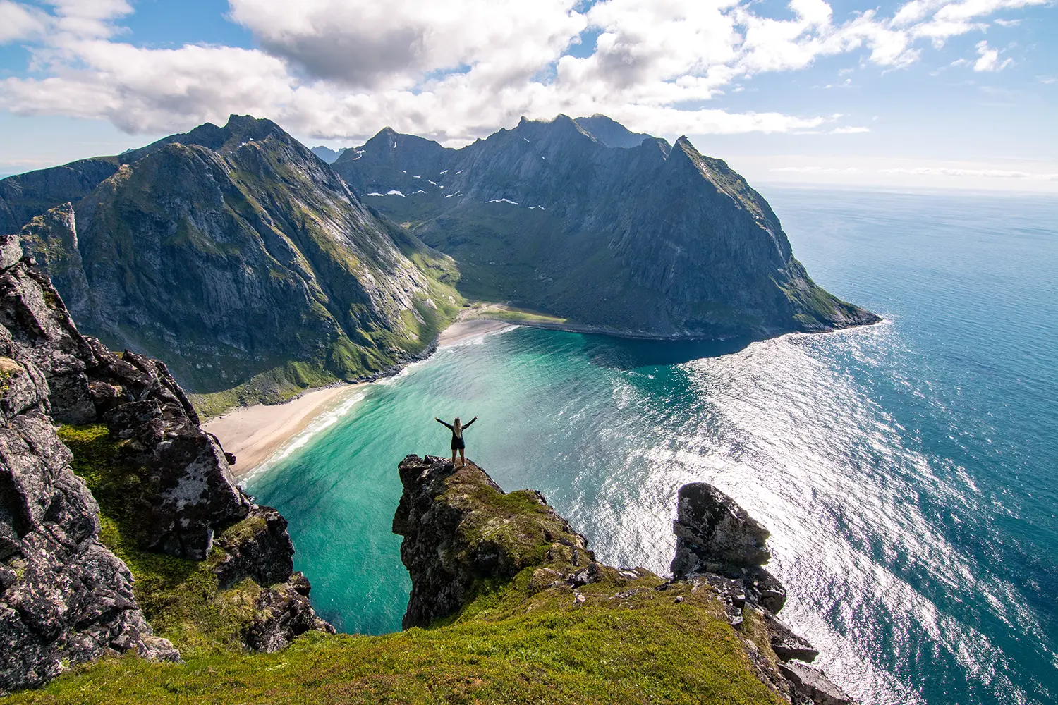 Woman looking at stunning summer landscape and view towards Kvalvika Beach in Lofoten, Norway