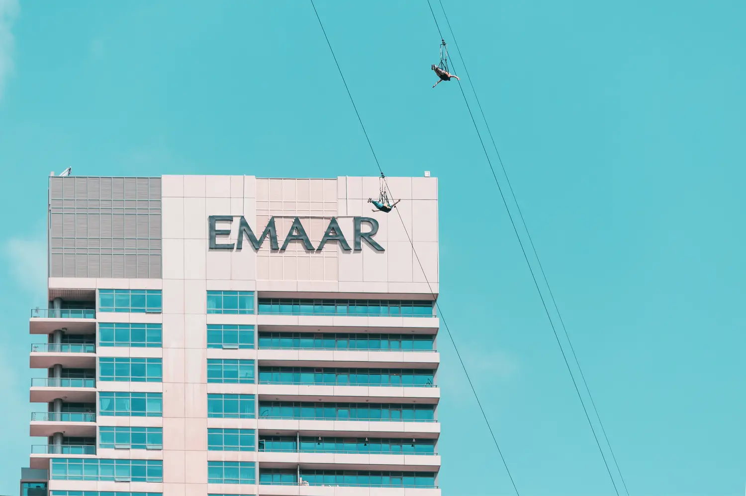 Two adventurers fly down a zip line rope in an extreme flight in Dubai Marina