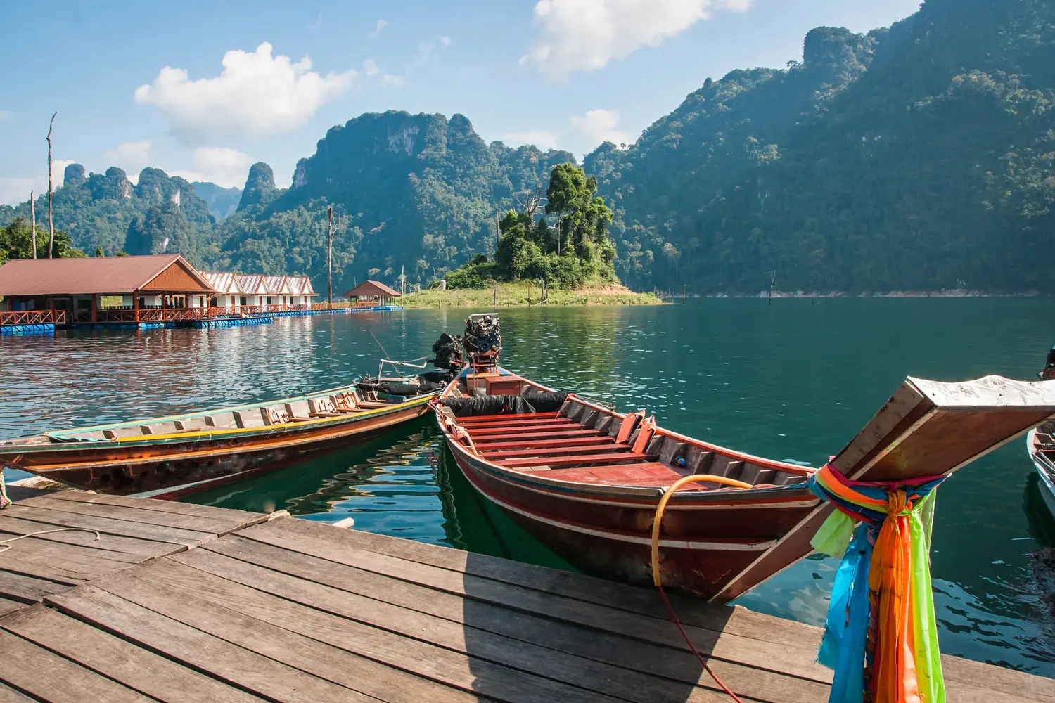 Floating houses and long tail boats at Cheow Larn lake at Khao Sok National Park in Thailand