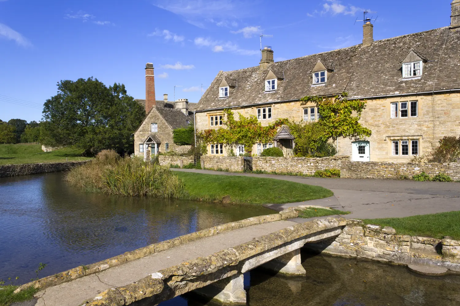 Idyllic old stone cottages at Lower Slaughter in autumn sunshine, Cotswolds, Gloucestershire, England, UK