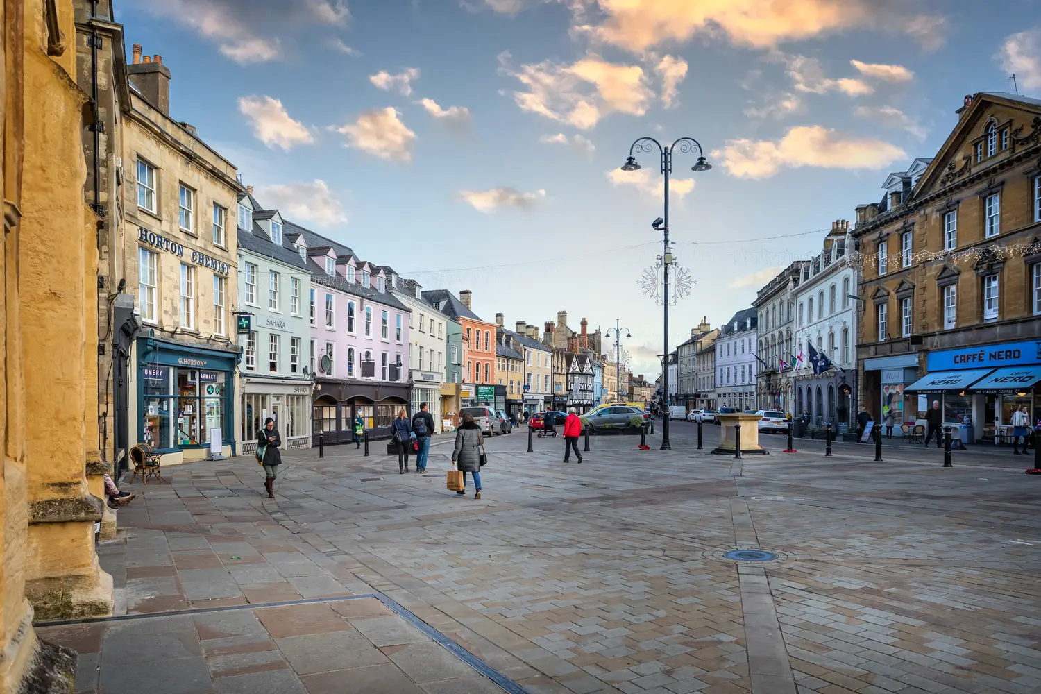 Shops and restaurants in Market Place at sunset in Cirencester, Gloucestershire, UK