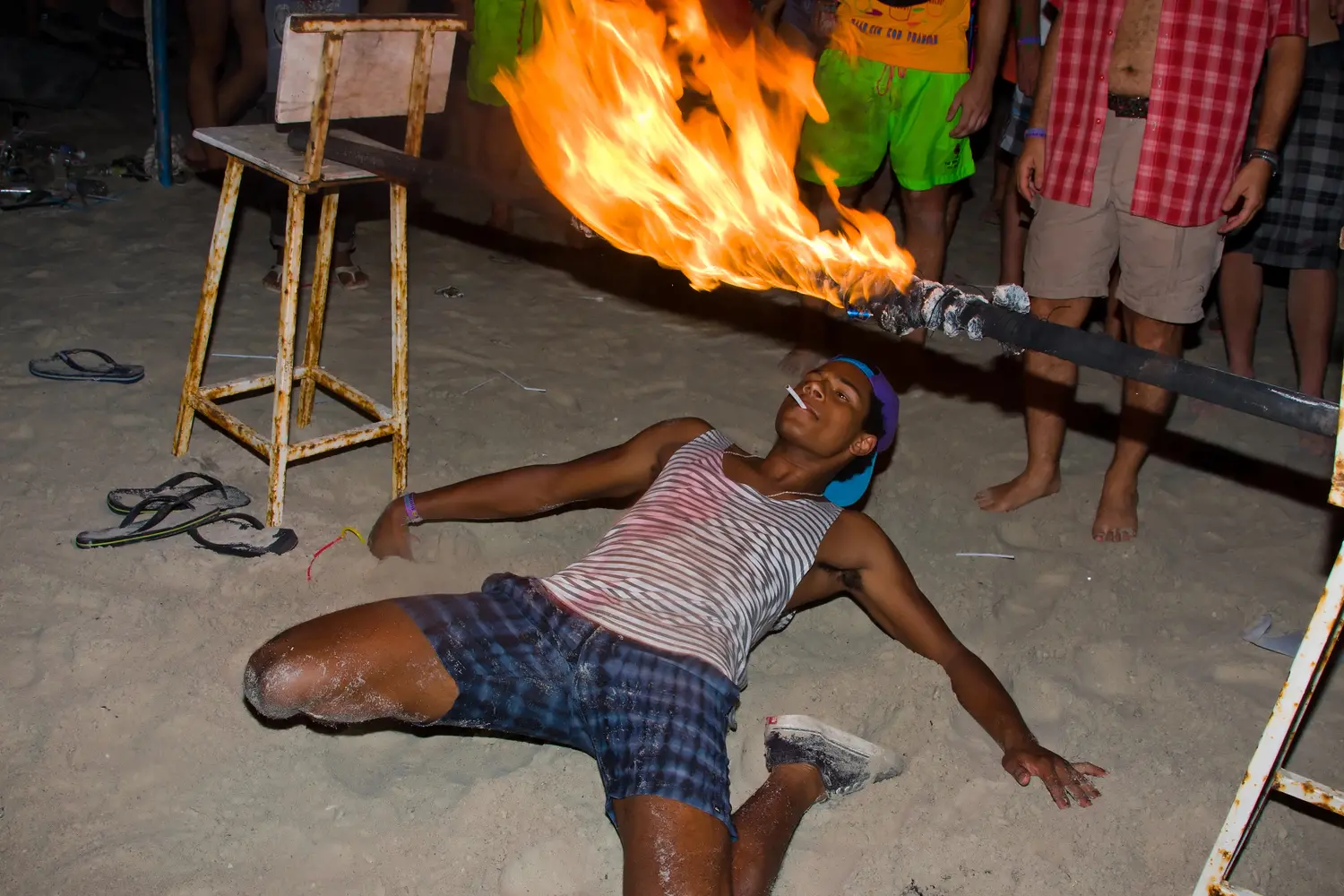 Guy attempting the flaming limbo stick challenge during Thailand's Full Moon Party in Koh Phangan, Thailand.