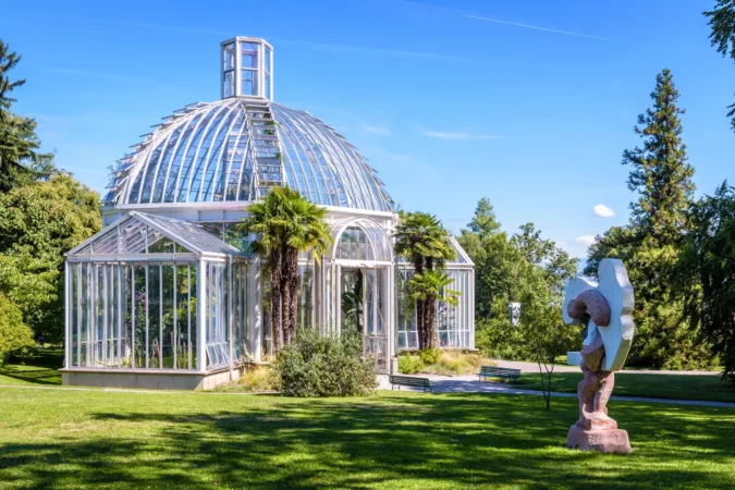 The temperate greenhouse in the Conservatory and Botanical Garden of Geneva and the sculpture "Portatore di zucche" by italian artist Michelangelo Pistoletto.
