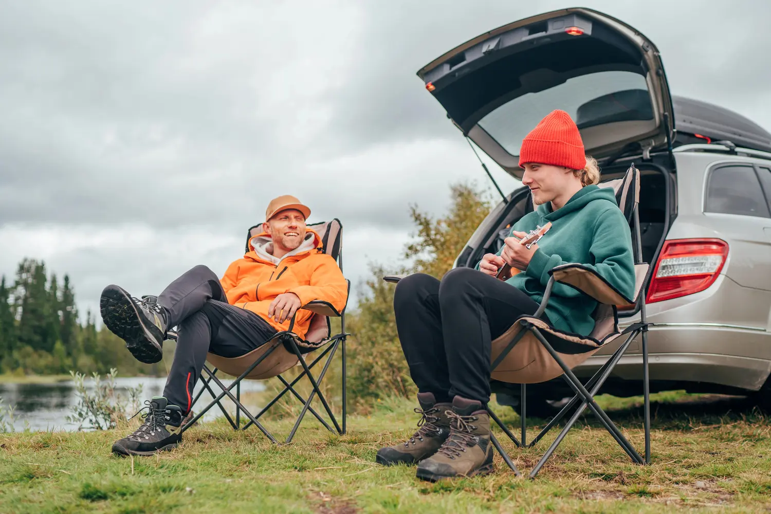 Couple sitting in camp chairs in front of car and car camping in autumn